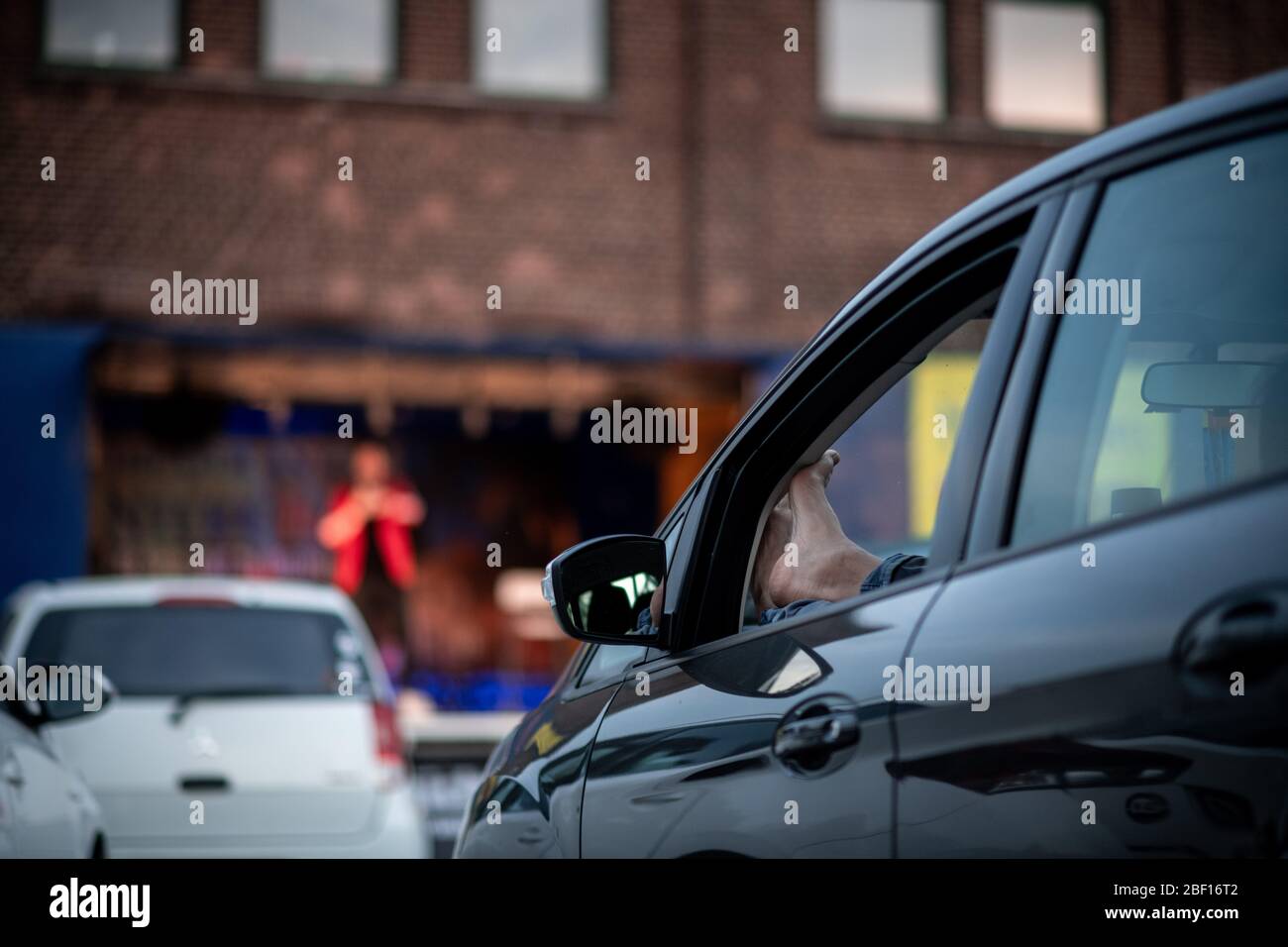 Oberhausen, Deutschland. April 2020. Ein Zuschauer hört sich das Programm 'Suddly Serious' an. Das Theater an der Niehburg in Oberhausen bietet ein Drive-in-Theater. Künstler treten auf einer Bühne auf einem Parkplatz vor den Zuschauern in Autos auf. Quelle: Fabian Strauch/dpa/Alamy Live News Stockfoto