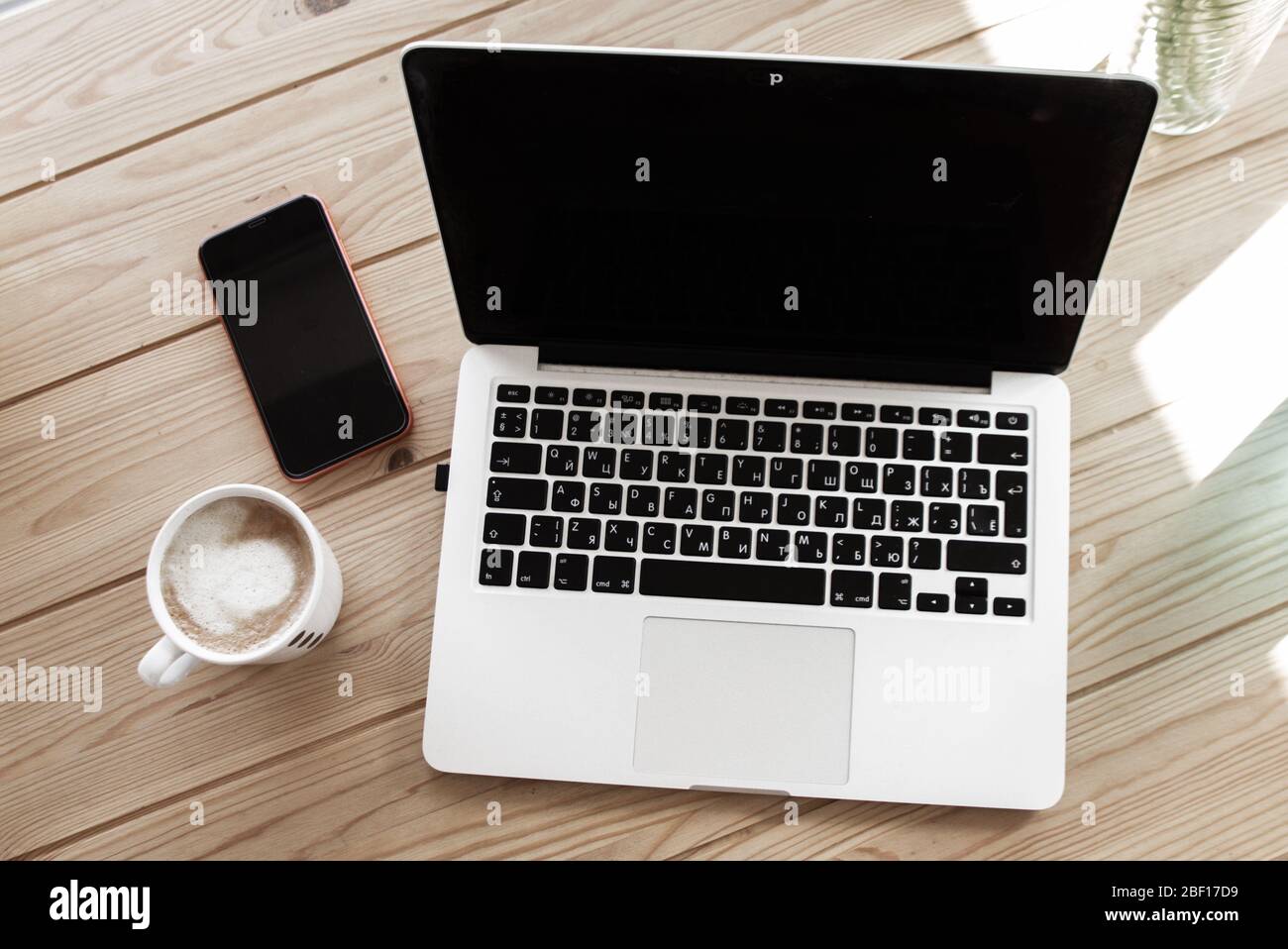 Heller Arbeitsbereich, Holzschreibtisch mit Laptop, Kaffeetasse und Smartphone. Stockfoto