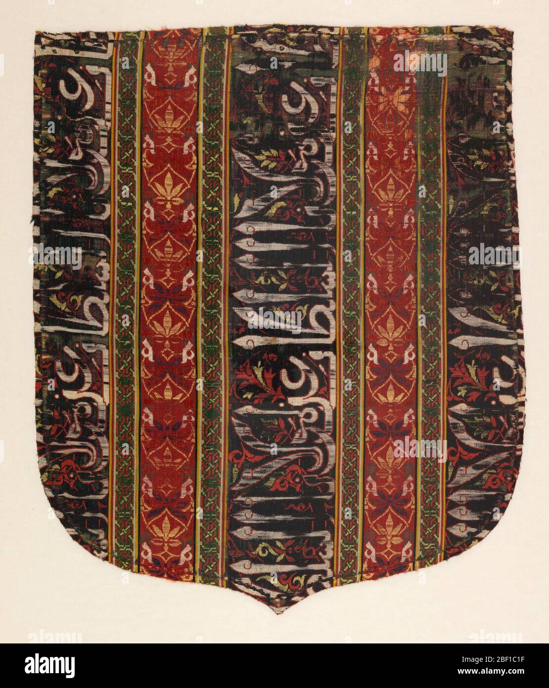 Cope Haube Fragment. Schildförmige Cope-Kapuze, vertikal gestreift mit breiten dunkelblauen Streifen mit arabischen Inschriften in Weiß, Rot und Gelb, abwechselnd mit schmaleren roten Streifen mit konventionalisierten Blumen- und Blattmotiven in Dunkelblau, Gelb, Grün und Weiß. Stockfoto