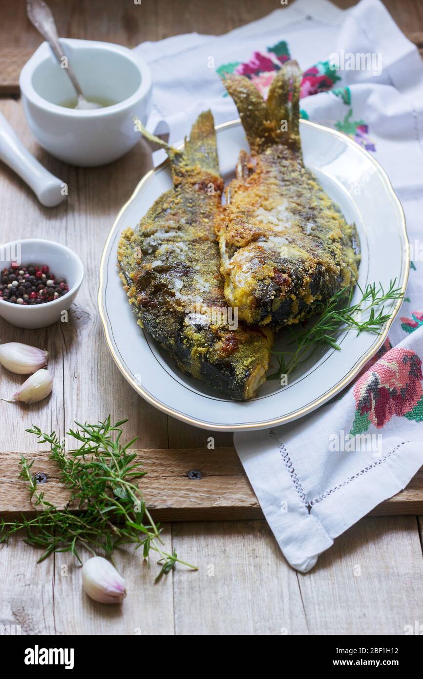 Traditionelle moldauische oder rumänische Gericht, gebratener Fisch in Maispanierel mit Knoblauchsauce serviert. Rustikaler Stil. Stockfoto