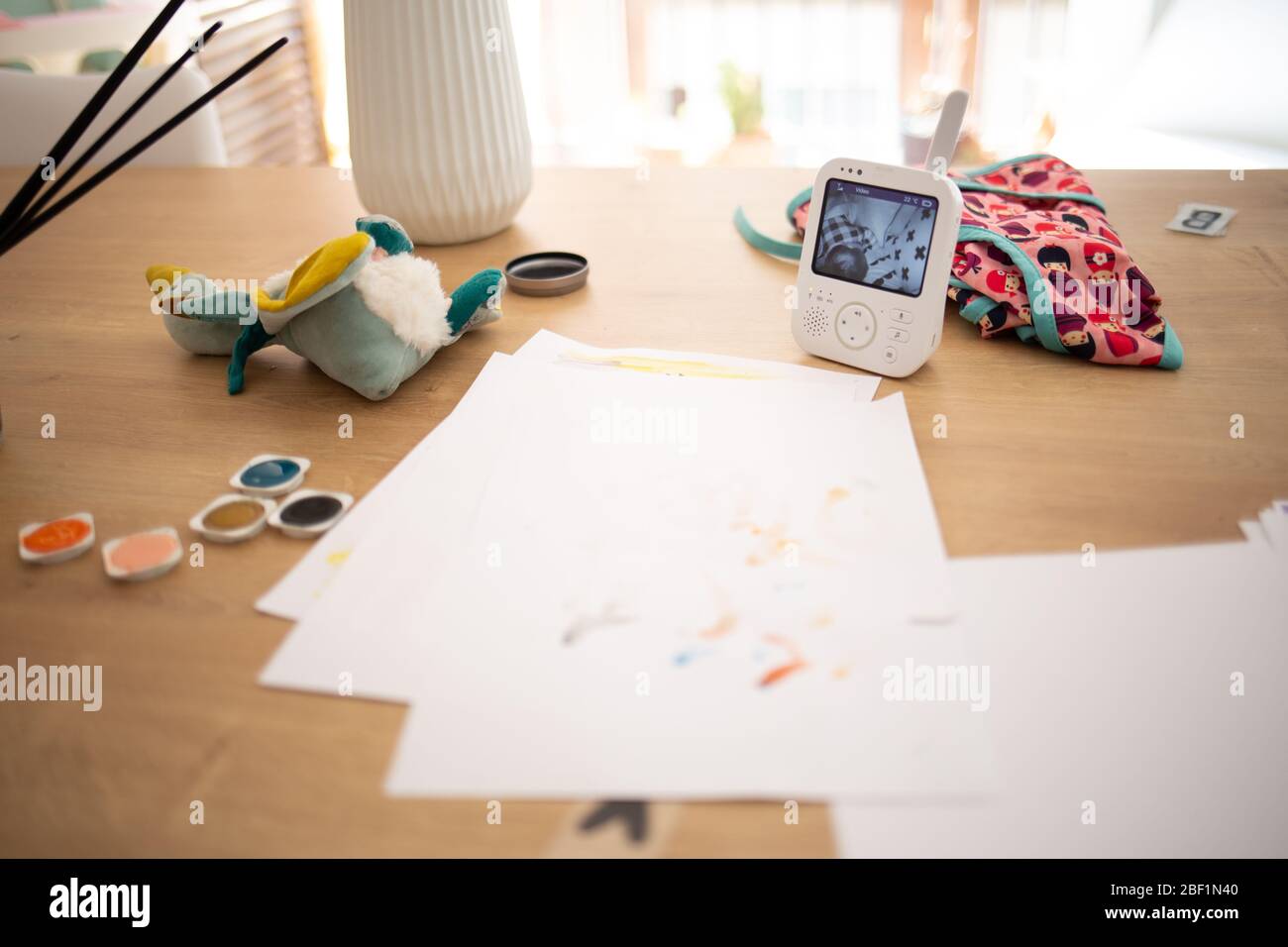 Heimarbeit mit Farbfarben, Spielzeug und Babykamerawächter auf einem Holztisch auf einer häuslichen Szene während der Quarantäne Stockfoto