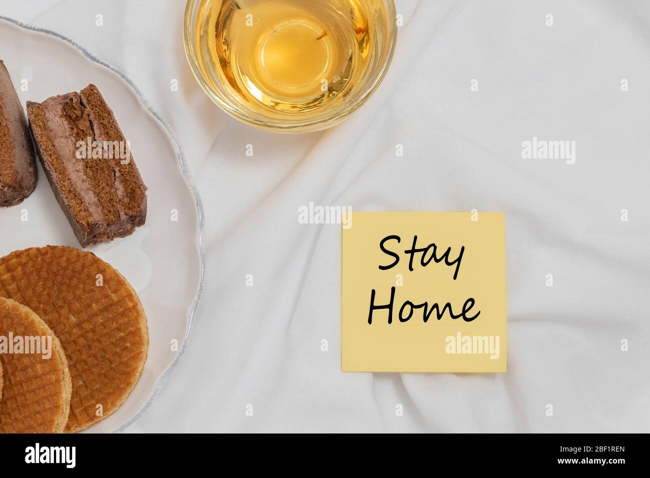 Bleiben Sie zu Hause Phrase auf gemütlichen Hause Hintergrund mit einer Tasse Tee und Süßigkeiten. Selbstisolierung Motivation während COVID-19 Ausbruch Konzept Stockfoto
