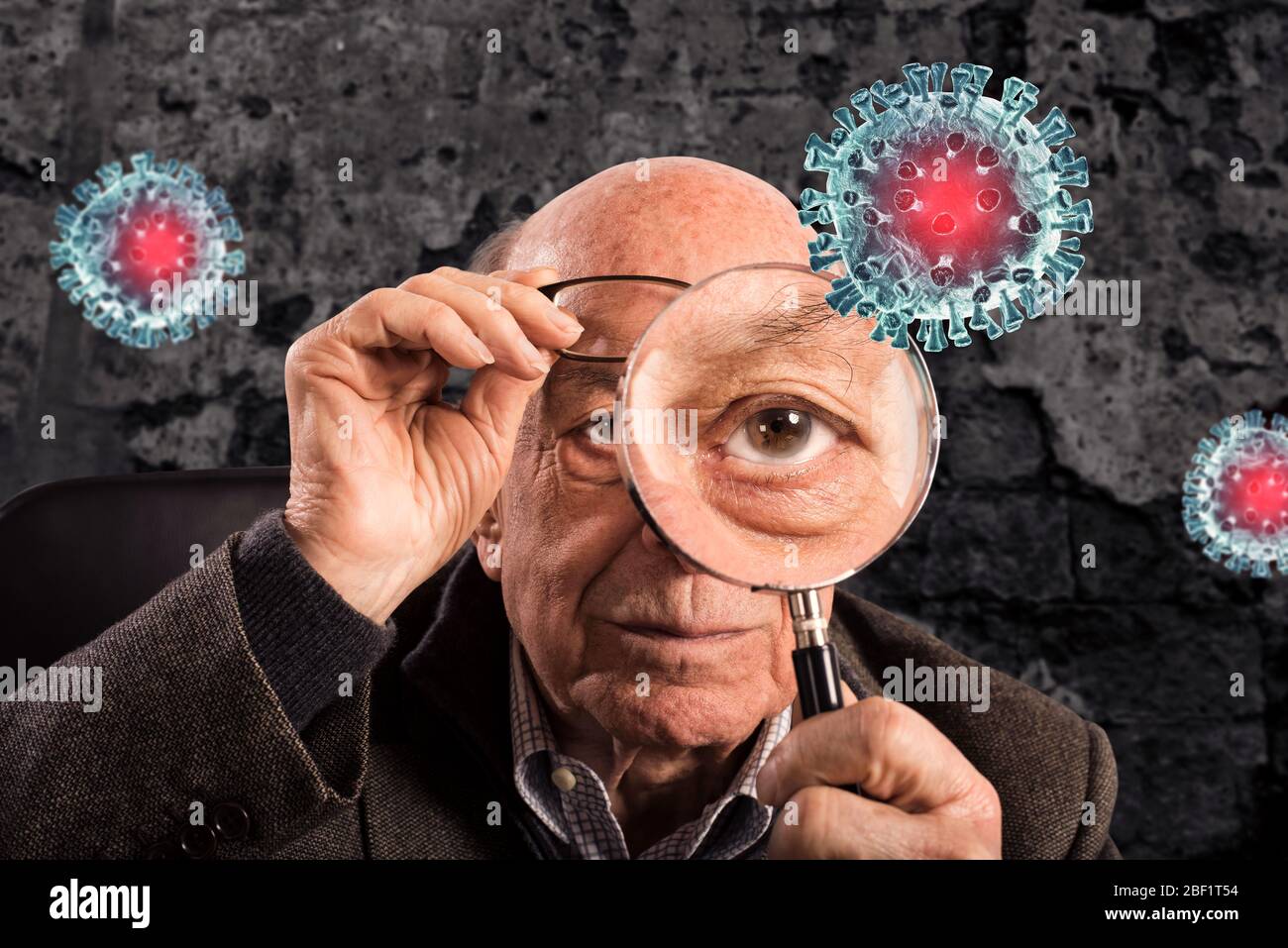 Älterer Mann sieht mit Lupe ein Covid19 Coronavirus Stockfoto