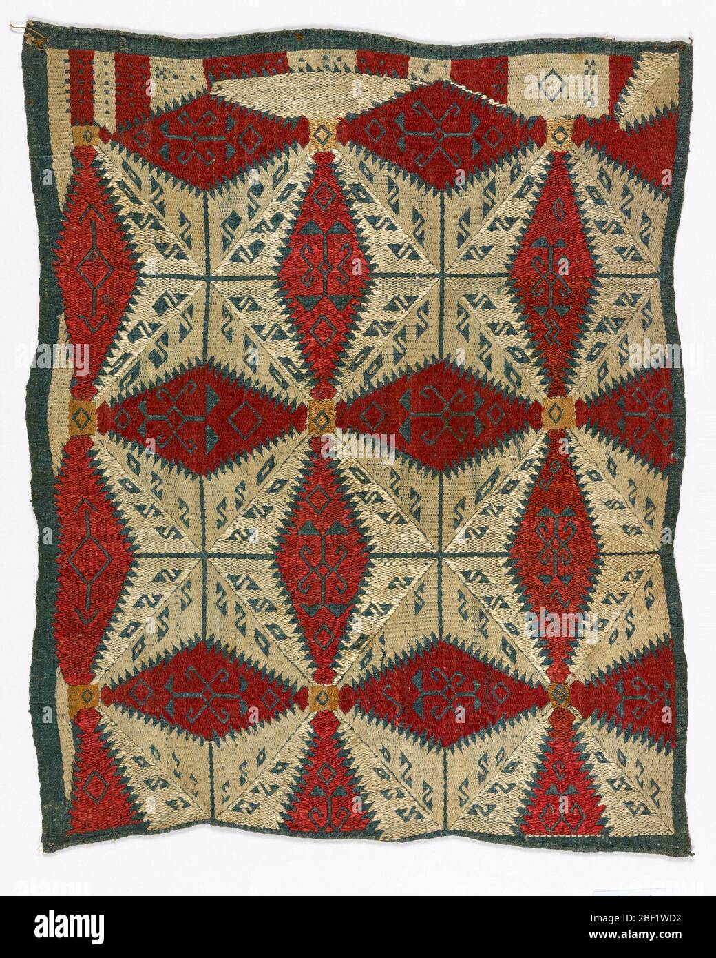 Kissenbezug. Kissenbezug aus schwerem, handgewebtem Leinen, gefärbt in Indigo. Bestickt mit roter, weißer und Buff-Seide in einem geometrischen Design aus Stern- und Blattformen. Die Motive haben Sägezahn-Kanten und enthalten kleinere Pflanzenmotive, die in blauem Leinen reserviert sind. Stockfoto