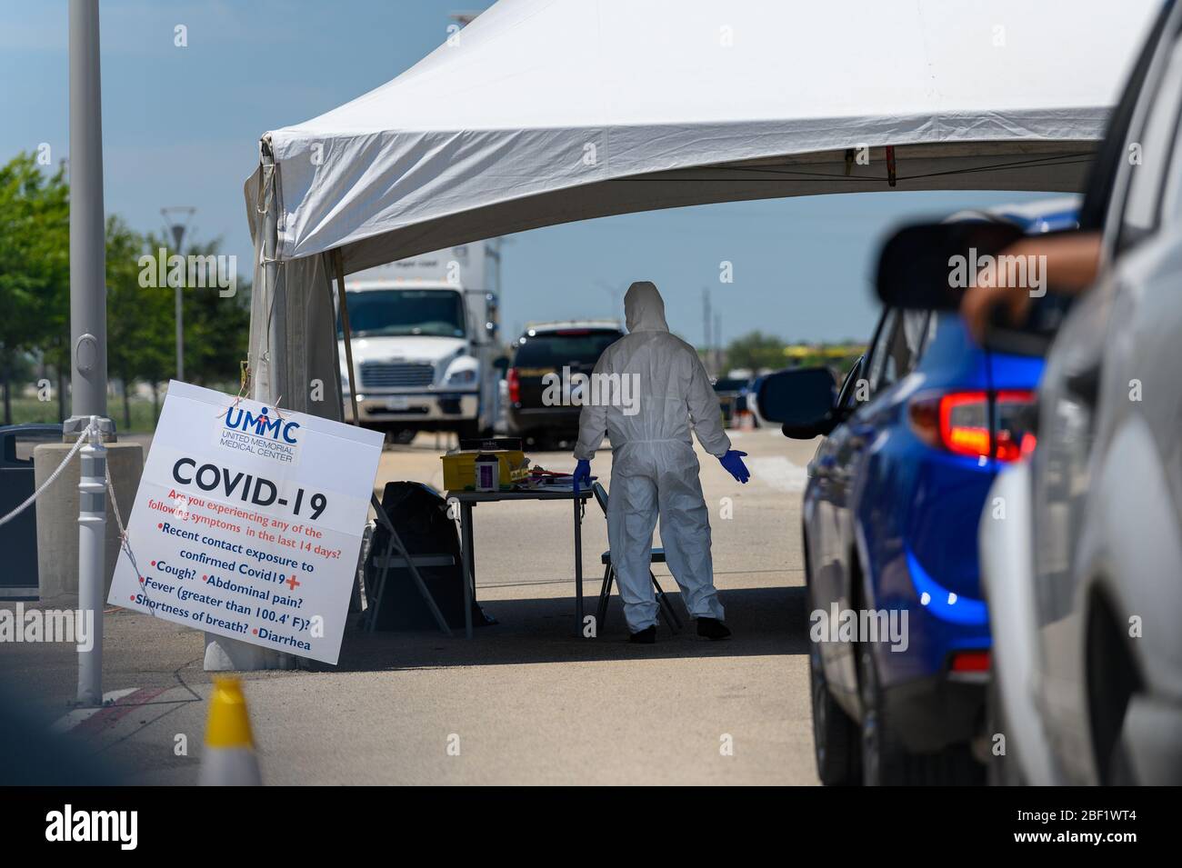 Sugar Land, Texas - 16. April 2020: In voller Schutzkleidung trägt ein Gesundheitsarbeiter Informationen von Personen, die in ihrem Auto an der T sitzen Stockfoto