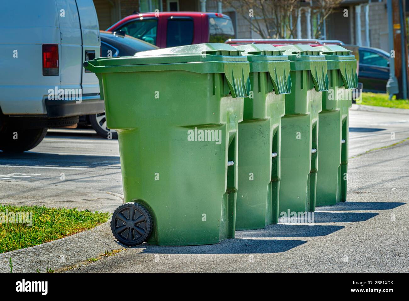 Horizontale Aufnahme von vier Müllcontainern in Wohnhäusern, die auf der Straße aufgestellt sind, um sie abholen zu können. Stockfoto