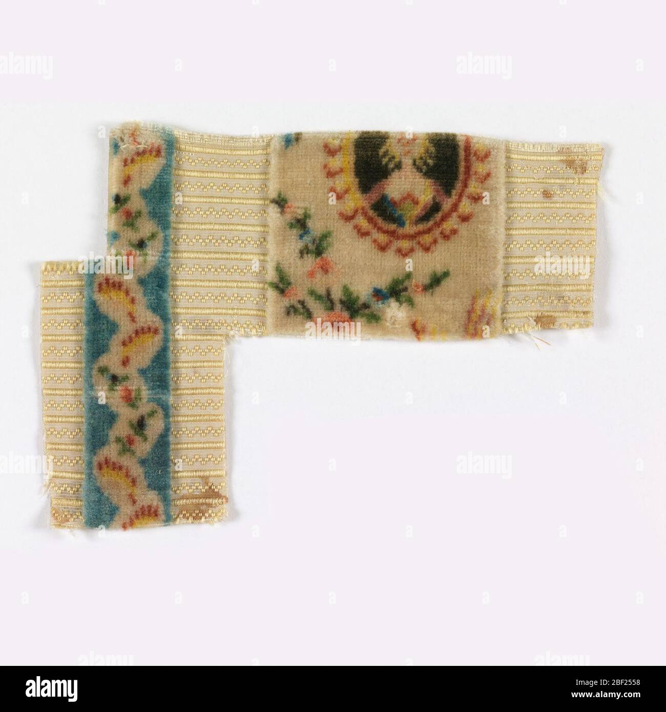 Fragment. Samtfragment. Weißer Boden mit horizontalen Streifen und Sägezahn-Linien in ergänzender gelber Kette. Vertikale blaue Streifen mit geschnittenen Flor mit floralen Reben und ein großes zentrales Band mit einem partiellen Porträtmedaillon mit floralen Blüten. Stockfoto
