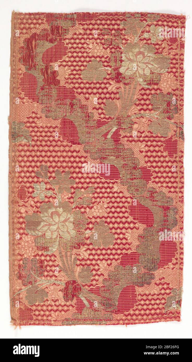 Textilfragment. Seidenbrokatfragment in Burgund und Creme mit einer Serpentinenlinie von C-Kurven mit Blumensträußen. Knospen in Silber brokat. Stockfoto