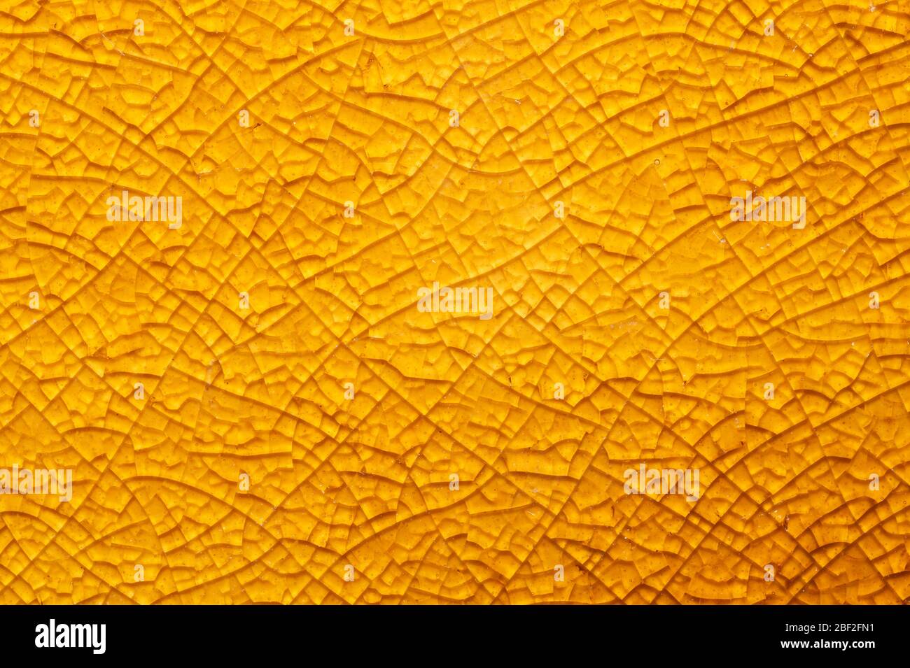Gebrochene keramische Textur Nahaufnahme. Gebrochene Glashintergrund. Abstrakte gelbe Oberfläche. Gebrochene Mosaik Glas Makro Hintergrund Stockfoto