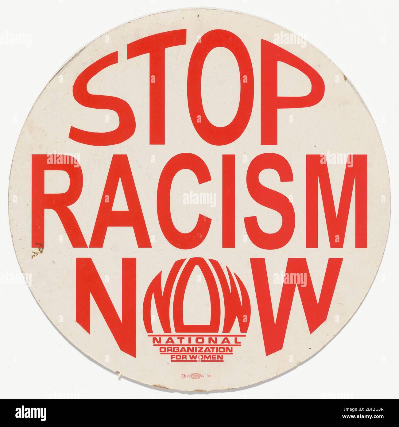 Plakat mit STOP RASSISMUS JETZT Nachricht. Ein runder Karton-Plakette, der auf jeder Seite mit weißem Papier bedeckt ist und roten Text trägt: [STOP / RACISM / NOW]. Stockfoto