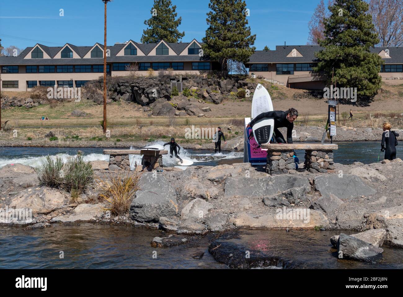 Mehrere Surfer warten auf die von Menschenhand geschafften Stromschnellen in Bend, Oregon während der Covid-19-Pandemie. Stockfoto