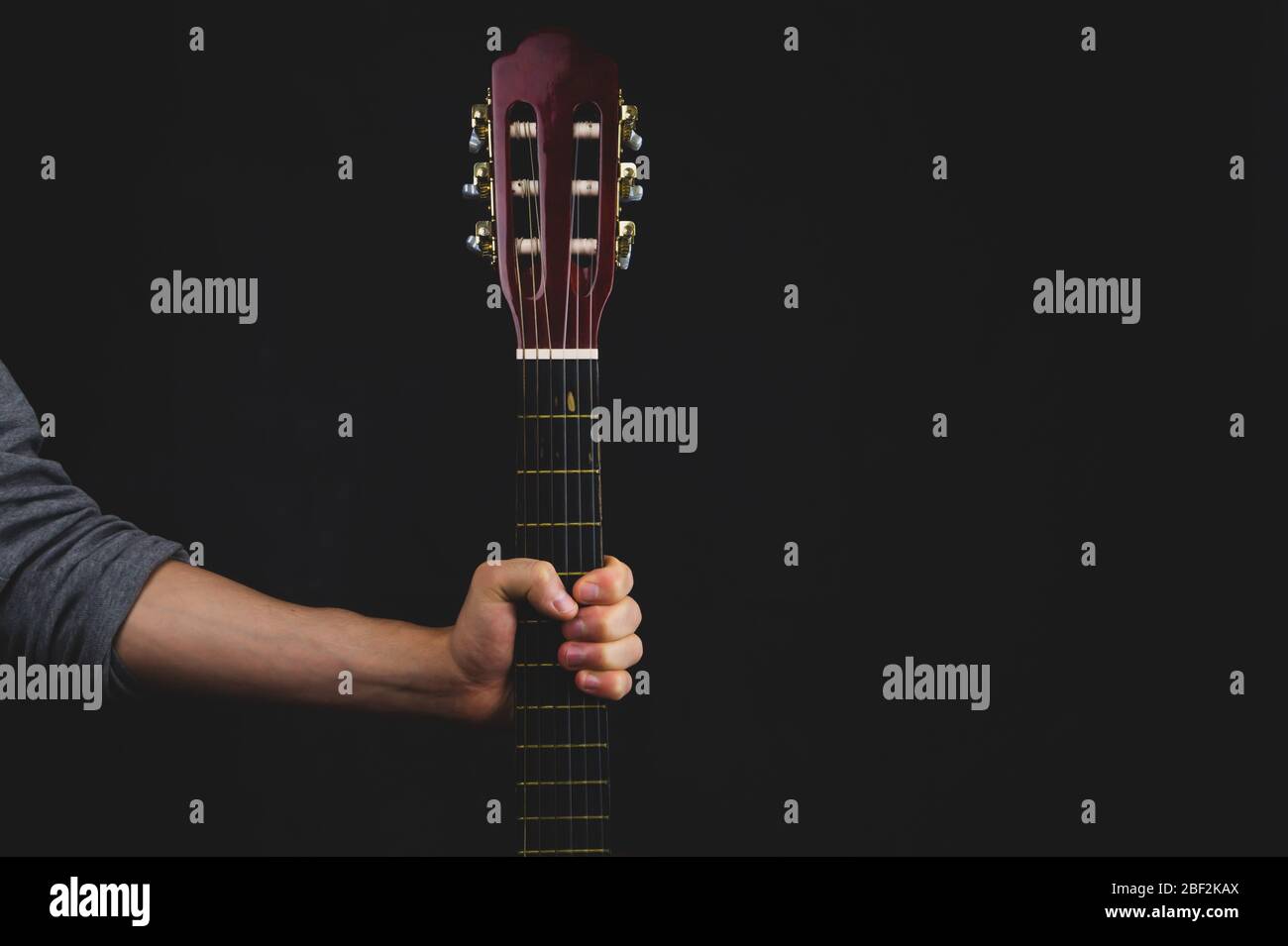 Hand hält akustische Gitarre. Musikinstrument auf schwarzem Hintergrund Stockfoto