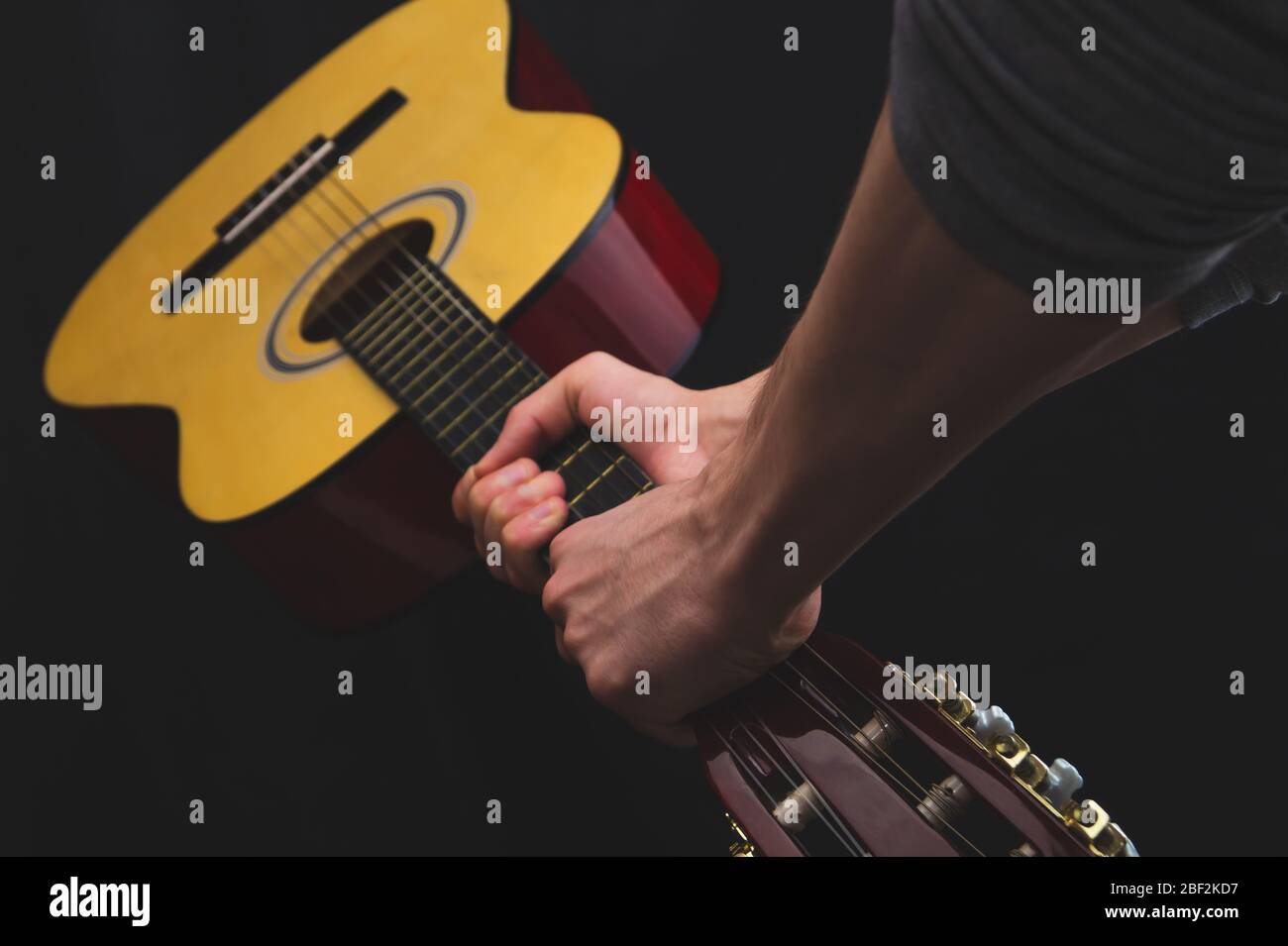 Hände halten akustische Gitarre. Musikinstrument auf schwarzem Hintergrund Stockfoto