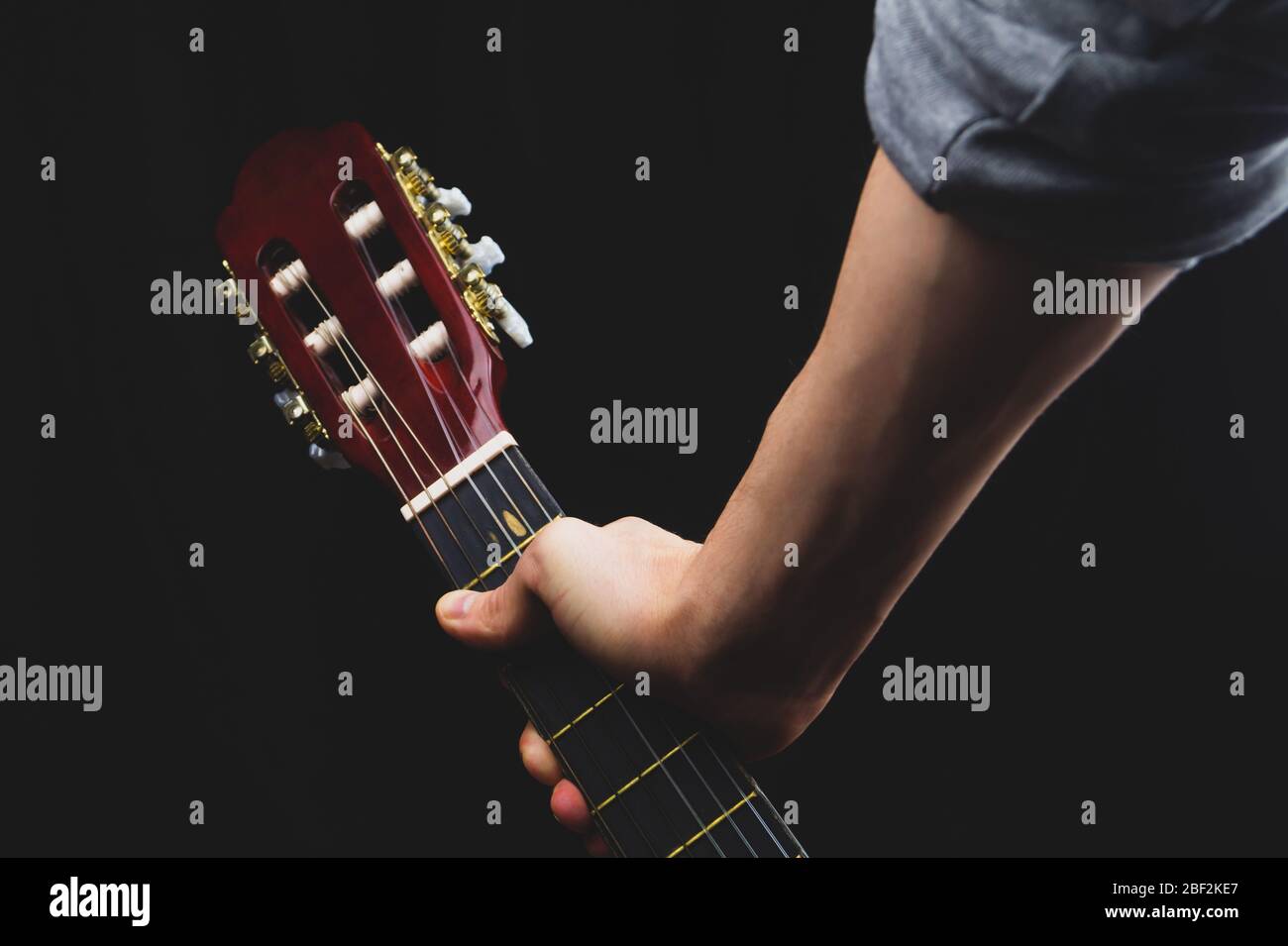 Hand hält akustische Gitarre. Musikinstrument auf schwarzem Hintergrund Stockfoto