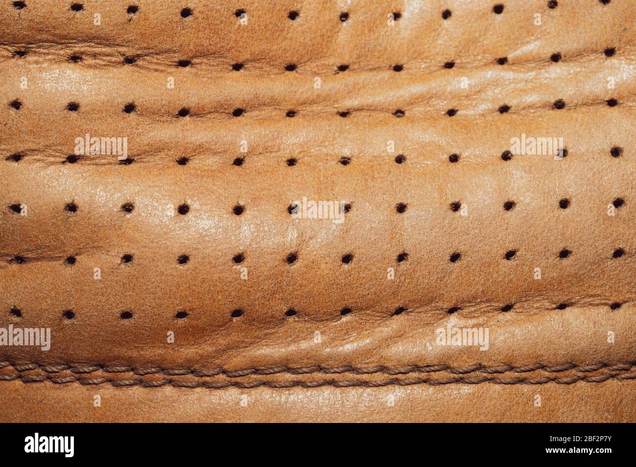 Braune Lederstruktur mit Löchern und Nähten. Knittertes Material mit Nähten Makro Hintergrund Stockfoto