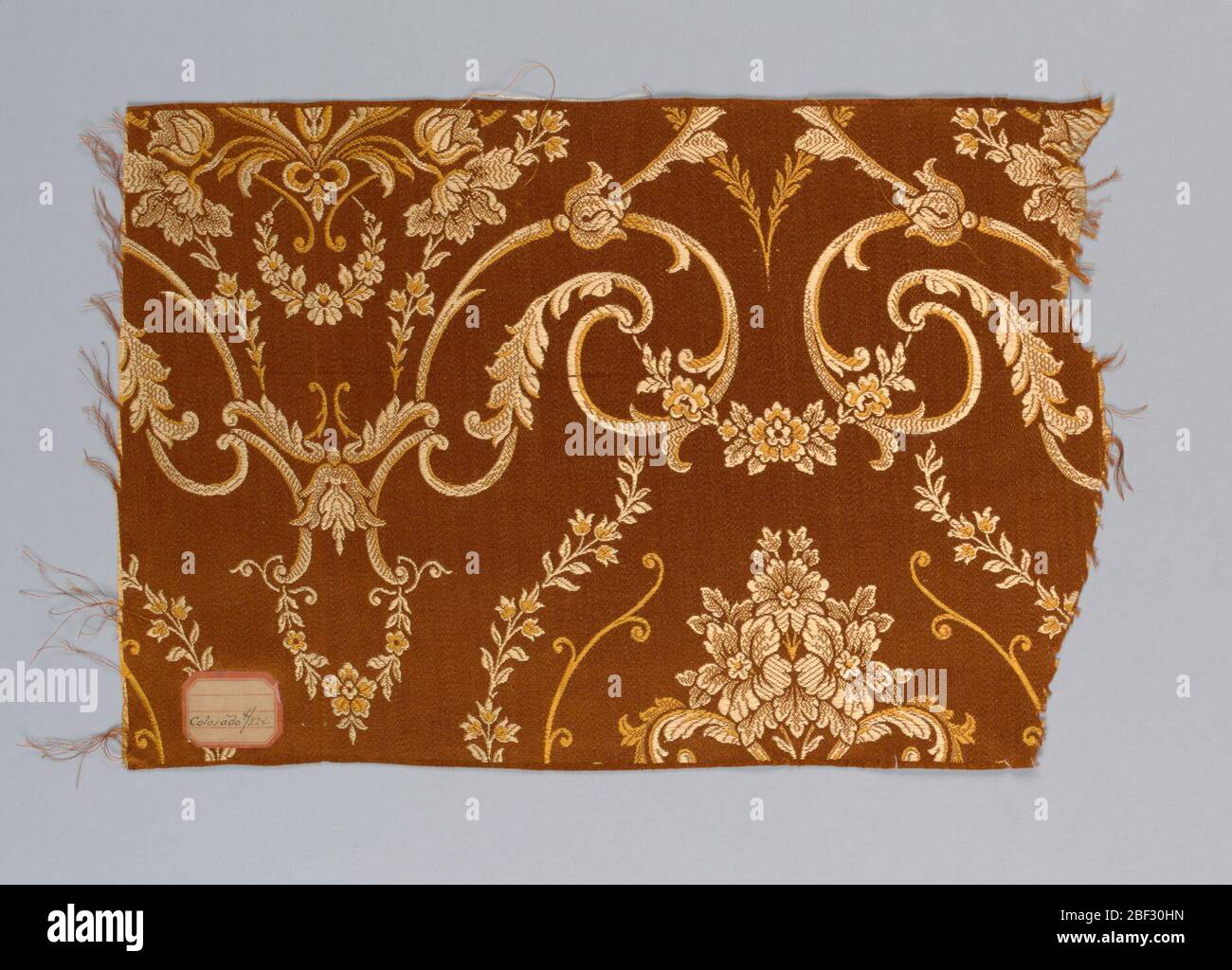 Probe. Rot/braun Warp und zwei Schattierungen von Gold Farbe Schuss macht ein florales Arabeske Muster Stockfoto