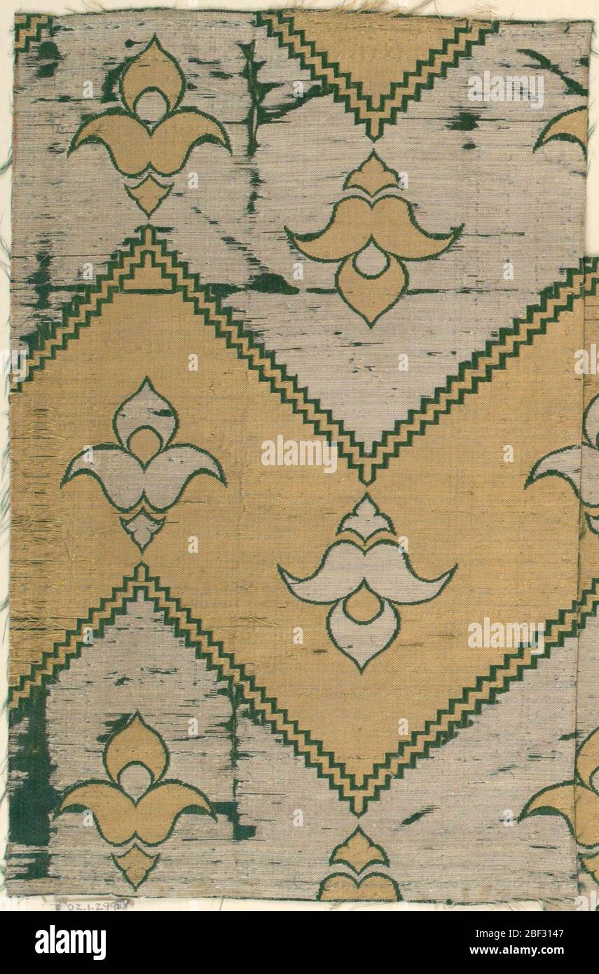 Fragment. Breite horizontale Zickzackbänder abwechselnd Silber und Gold, getrennt durch zwei feine Zickzacklinien aus Grün. Jedes Band enthält Trefoils der entgegengesetzten Farbe (Silber auf Gold oder Gold auf Silber), die Richtung wechseln, in grün umrandet. Stockfoto