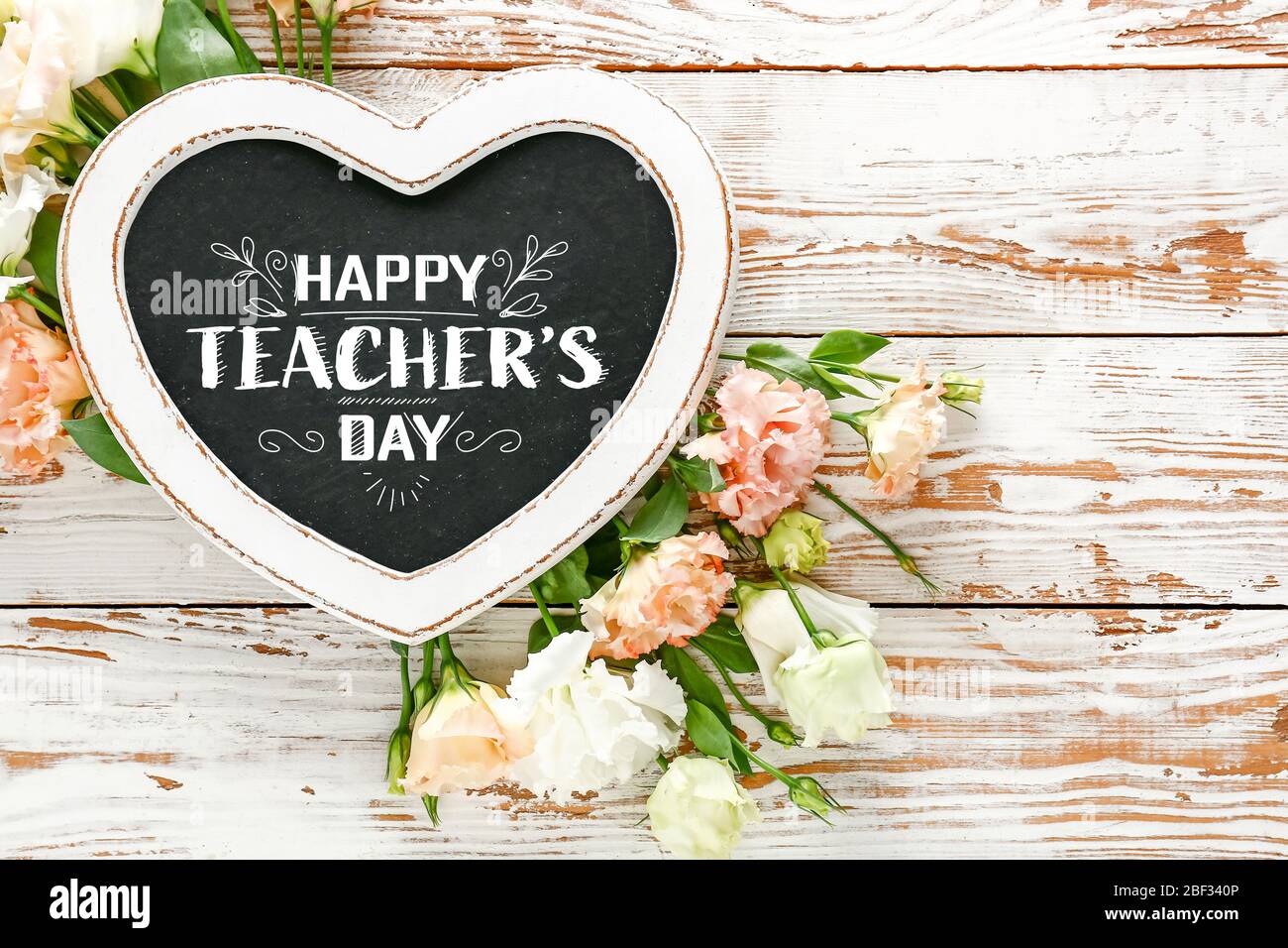 Rahmen mit Text GLÜCKLICH LEHRER TAG und schöne Blumen auf Holzhintergrund Stockfoto