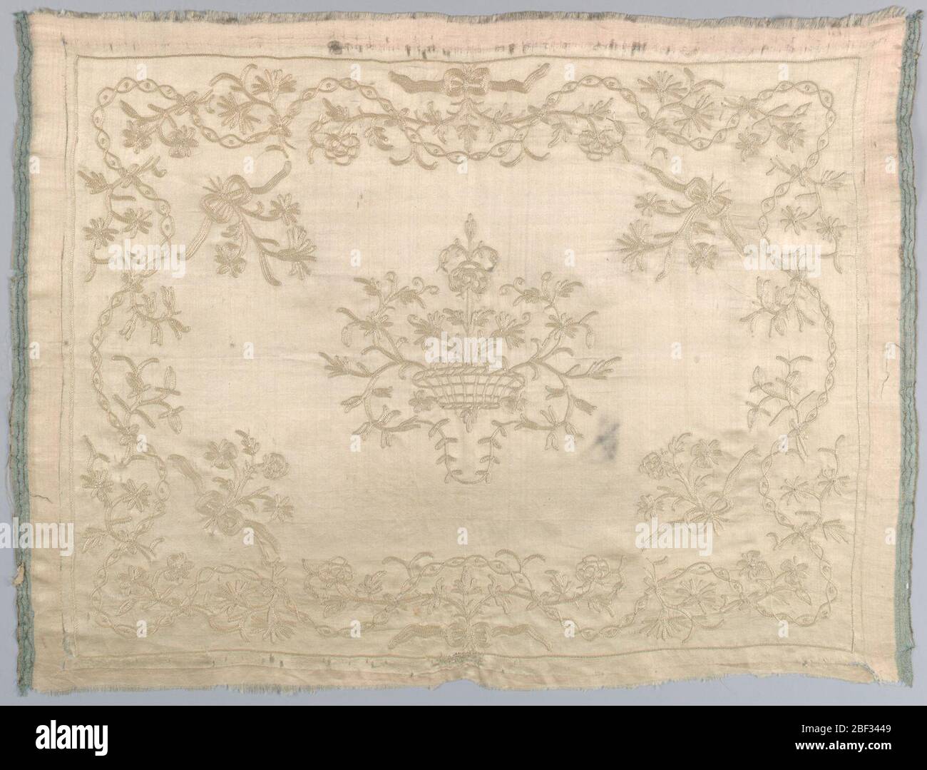 Textil. Elfenbein (ursprünglich rosa) Satin geschliffen. Horizontale rechteckige Platte. Zentraler symmetrischer Korb mit Blumen. Rand der Serpentin Verflechtung Linien umschließen Punkte. Blumige Sprays, die aus Serpentinen sprießen. Stockfoto