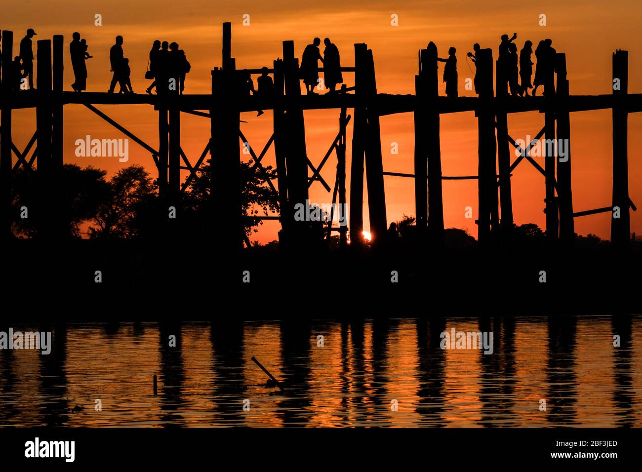 Mönche und Touristen treffen sich auf der U Bein Brücke bei Sonnenuntergang in Mandalay, Myanmar Stockfoto