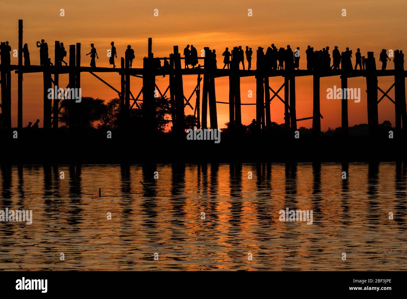 Mönche und Touristen treffen sich auf der U Bein Brücke bei Sonnenuntergang in Mandalay, Myanmar Stockfoto