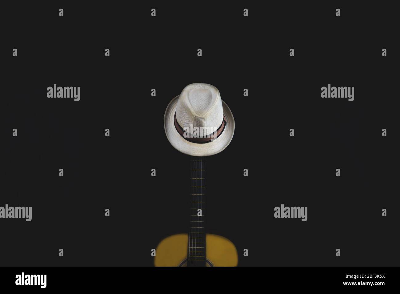 Weißer Hut hängt auf der Gitarre Griffbrett. Akustisches Musikinstrument. Saiten auf der Gitarre Hals Nahaufnahme Stockfoto