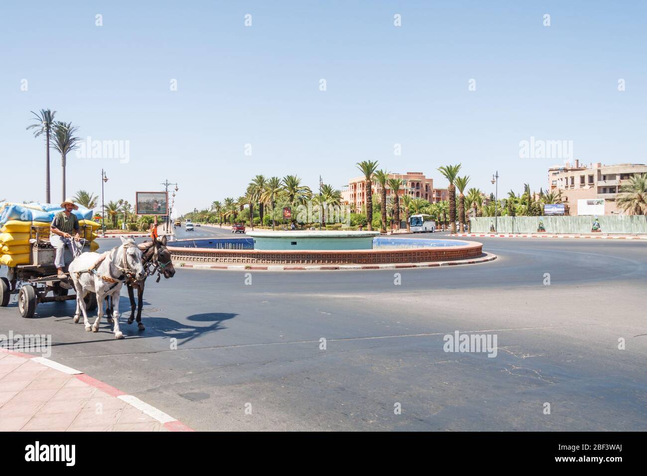 Marrakesch, Marokko - 8. September 2010: Mann auf Pferd und Wagen, der Waren um einen Kreisverkehr herum trägt. Diese Art des Transports wird noch genutzt. Stockfoto