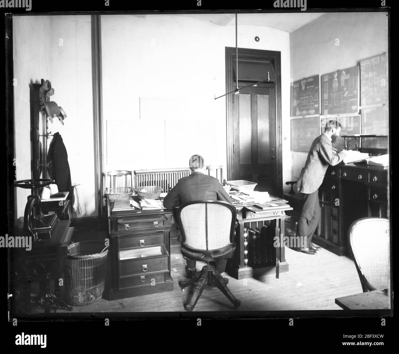 United States National Museum Office. Auch bekannt als 3676.Siehe auch Record Unit 95, Box 37, Folder 2.zwei unbekannte Männer im Büro im United States National Museum, heute bekannt als das Arts and Industries Building, mit Blaupausen an der Wand.Smithsonian Institution Archives, gem. 11-006, Box 009, Bild-Nr. Stockfoto