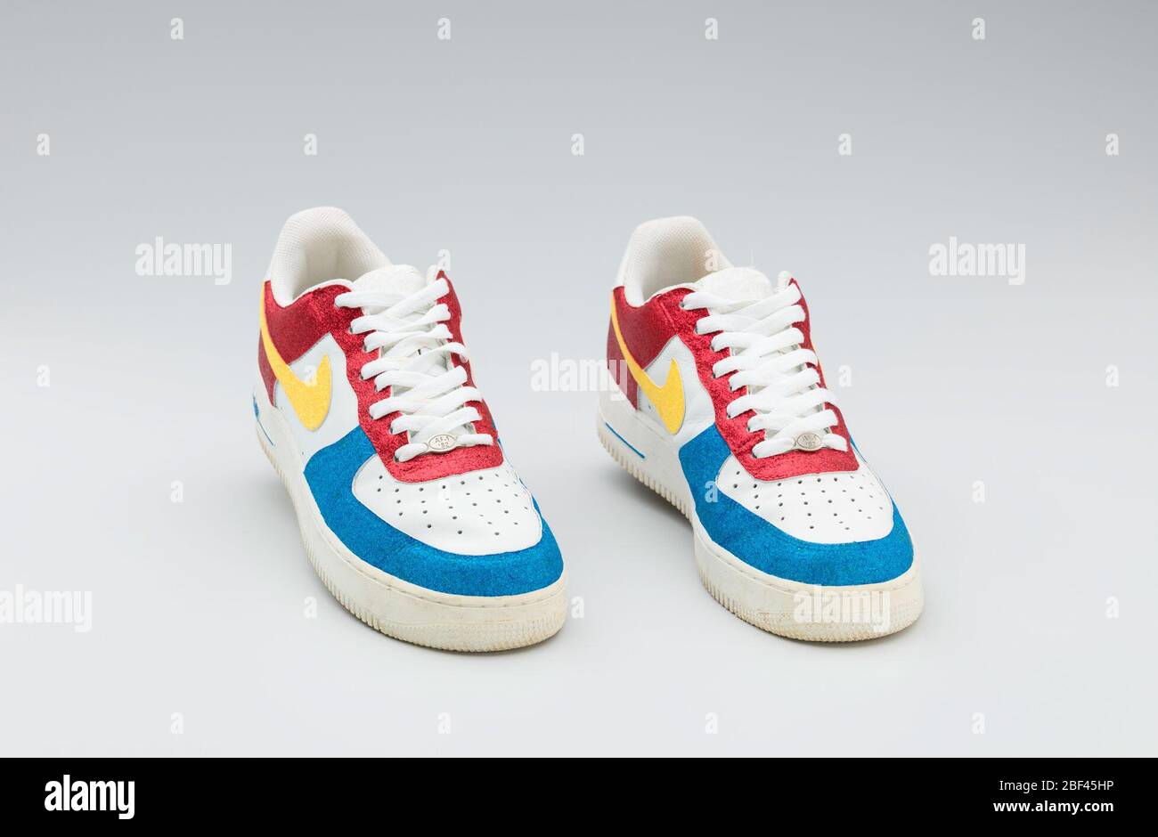 Nike Sneaker in Rot, Weiß, Gelb und Blau, getragen von Big Boi von Outkast.  Ein Paar weiße Nike Sneaker mit roten, blauen und gelben  Glitzerabschnitten, die von Big Boi von Outkast getragen
