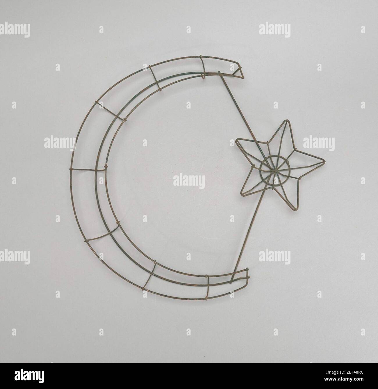 Drahtrahmen Halbmond Stern. In der trauernden Symbolik wurden Symbole der Ruhe und des Friedens populär und tröstende Optionen. Ein beliebtes Blumenrahmen-Design für Beerdigungen, die auf Ruhe angespielt wurde der Stern und Halbmond. Der Stern, wenn zusammen mit dem Halbmond, war symbolisch für den Schlaf einer reinen und unschuldigen Seele. Stockfoto