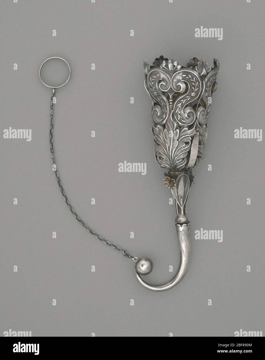 Blumenstraußhalter Blumen und Blätter Motiv. Trichterförmiger Blumenstraußhalter in Silber mit gebogenem Griff. Die durchbohrte Vase besteht aus sechs S-förmigen Schriftrollen mit Blumen- und Blattmotiven darin. Die Rollen ruhen auf drei strukturierten Blättern, die abwechselnd mit glatten, konischen Bändern aufliegen. Stockfoto
