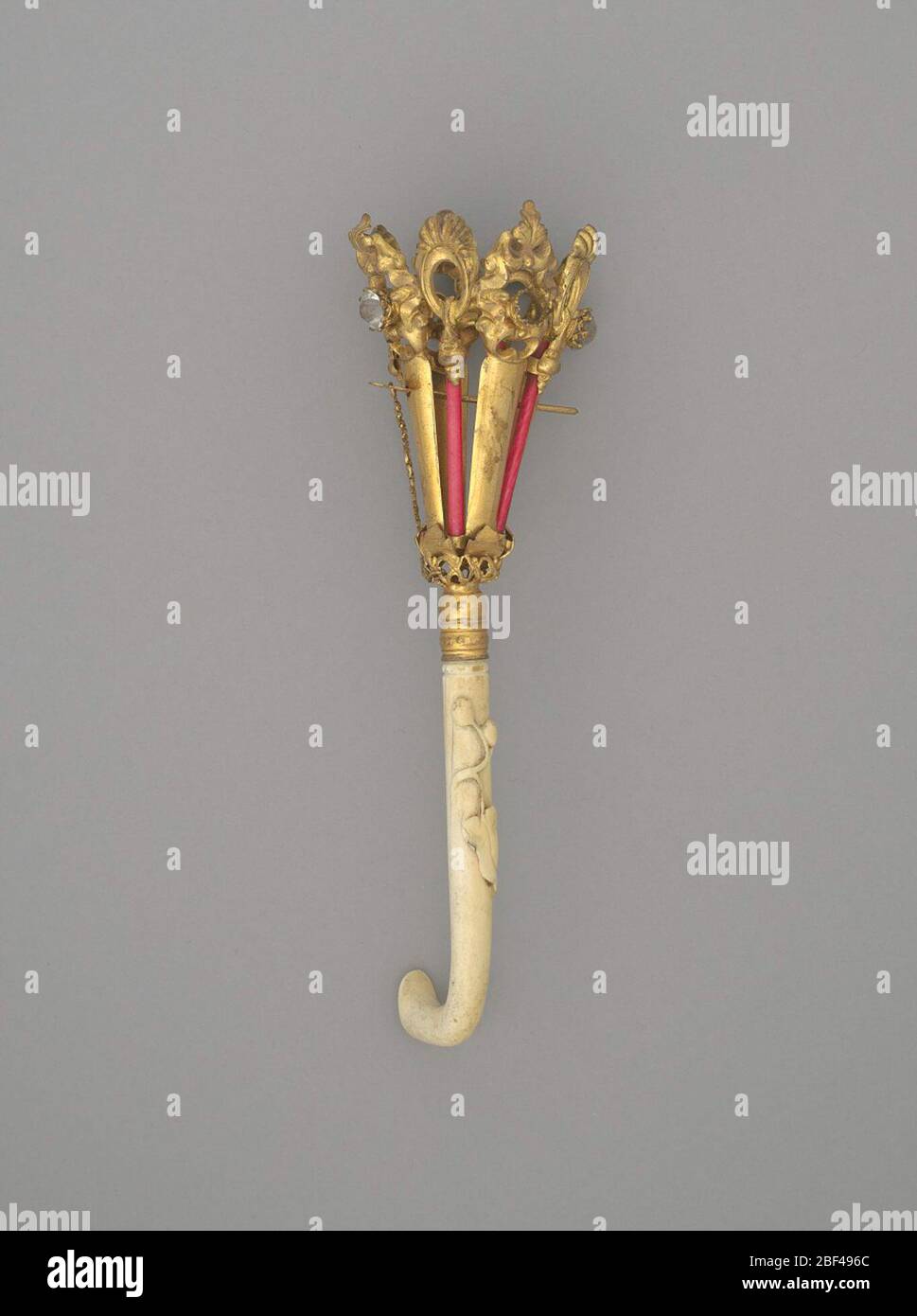 Blumenstraußhalter mit Steinchen und Knochengriff. Vergoldeter Messing-, Glas- und Knochenbouquet-Halter. Die große trichterförmige Vase besteht aus vergoldetem Messing und Elfenbeinröhren, die rot gefärbt wurden. Die Oberseite ist kunstvoll mit Rokoko Revival Stil durchbohrten Motiven, die im neunzehnten Jahrhundert populär waren gestempelt. Stockfoto