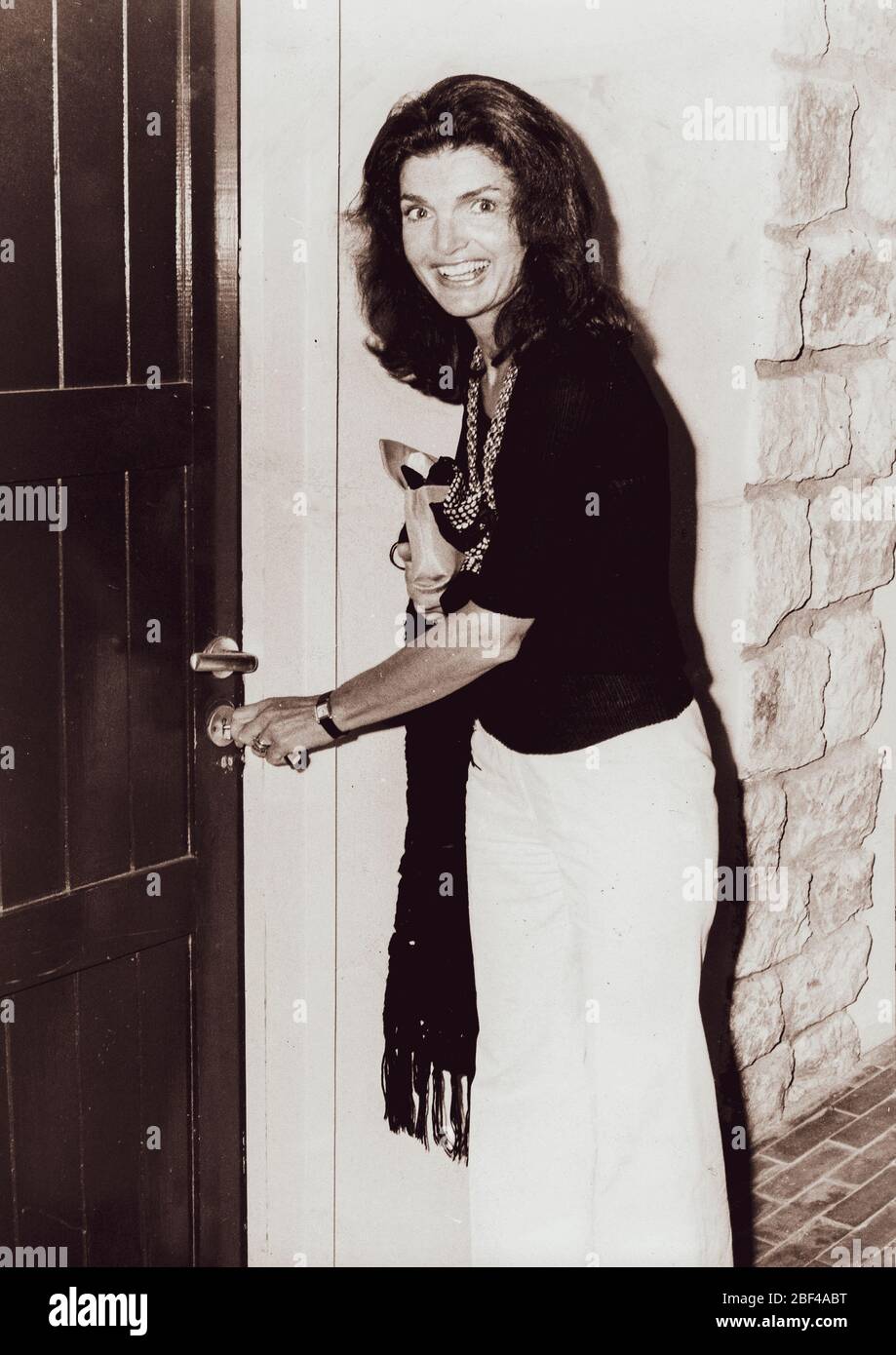 JACQUELINE KENNEDY ONASSIS, die ehemalige First Lady der Vereinigten Staaten, lächelt vor ihrer Haustür. Stockfoto