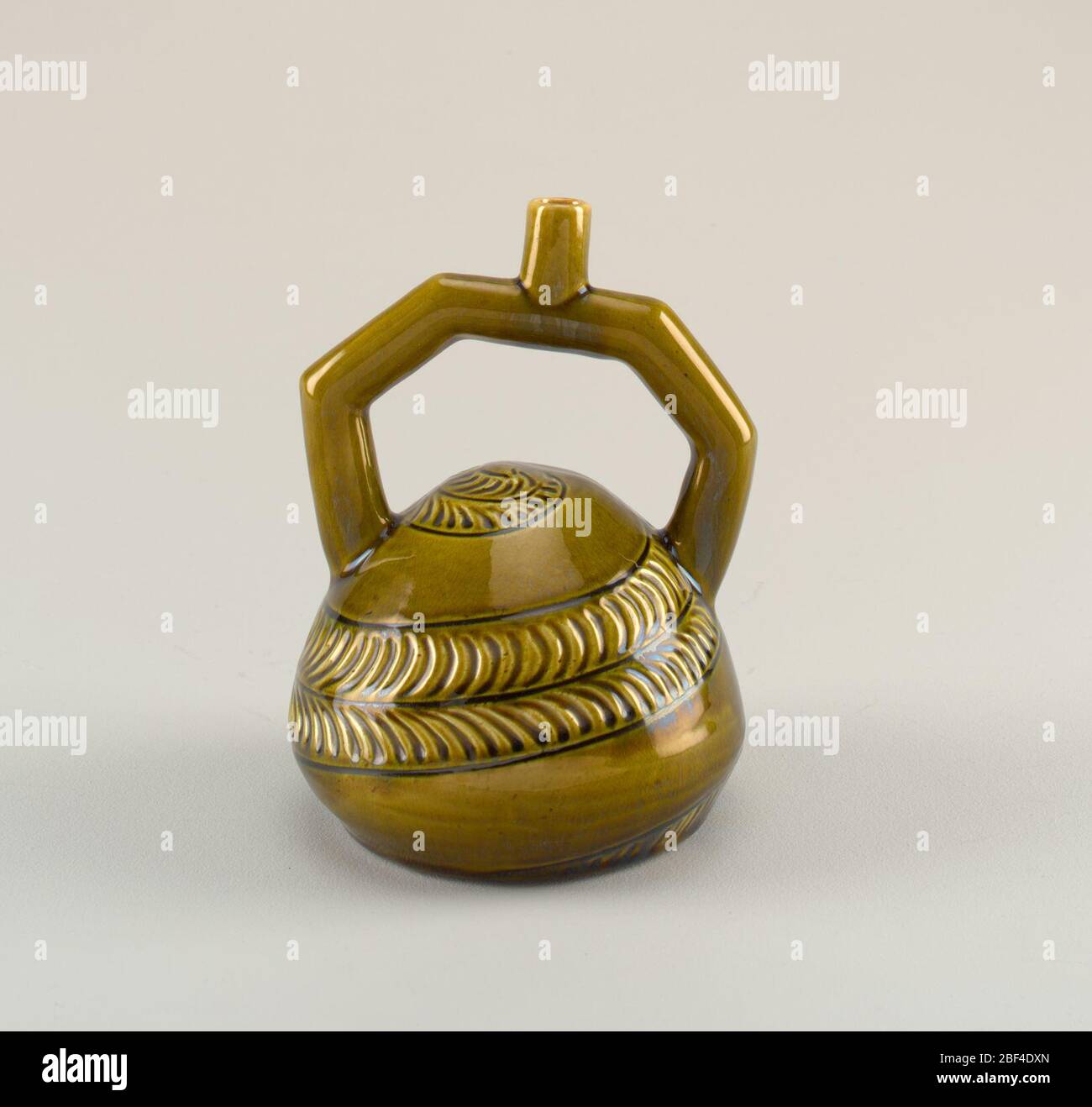 Behälter. Flasche mit Steigbügel und Auslauf mit spiralförmigem abstraktem Dekor und grüner Glasur. Stockfoto