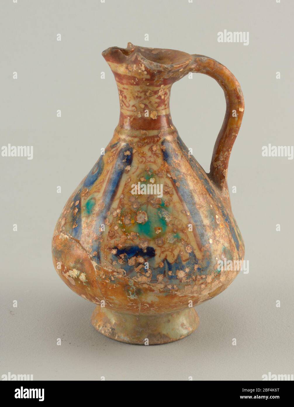 Ewer. Auf dem abfaßenden Fuß, ein pyriformer Körper, Kontraktion zu schmalen Hals mit Rand komprimiert, um Auslauf zu bilden. Schlaufengriff. Grünliche Glasur mit braun schillernden und türkisfarbenen Füllflächen zwischen großen Kufic Buchstaben. Stockfoto