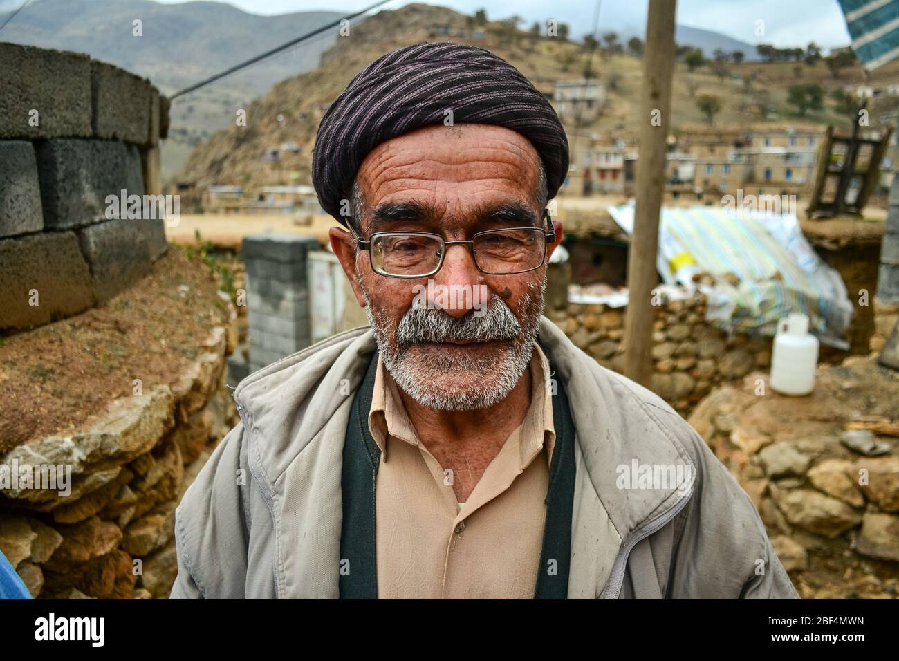 Palangan, iranisches Kurdistan - 15. November 2013: Porträt eines alten kurdischen Mannes mit Gesicht voller Falten, Brille und weißem Bart Stockfoto