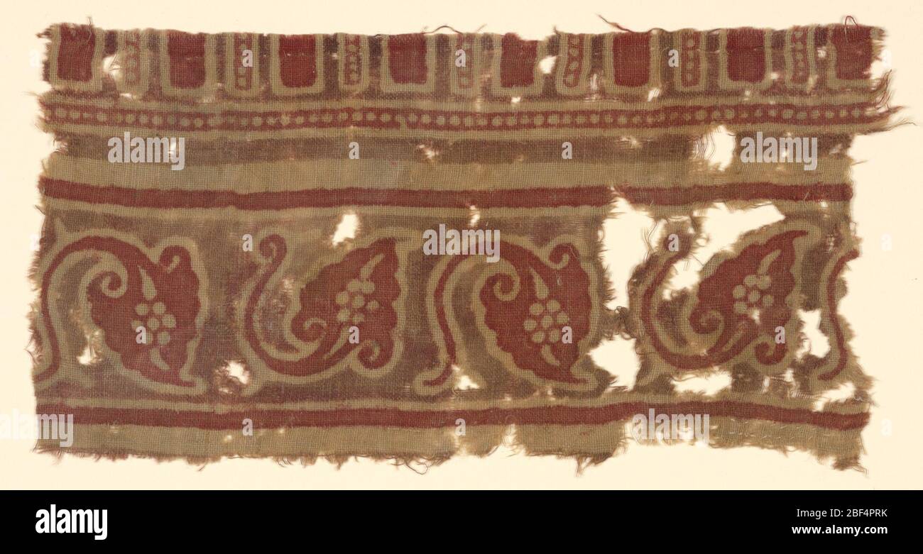 Fragment. Ungebleichte Baumwolle, Bordüre in rot und mattbraun (evtl. verblichenes Lila). Freistehendes Muster: Spitz zulaufende Blätter mit aktiv gebogenem Stamm, abwechselnd mit Blatt auf dem Kopf stehend, Zwischenräume in braun. Stockfoto