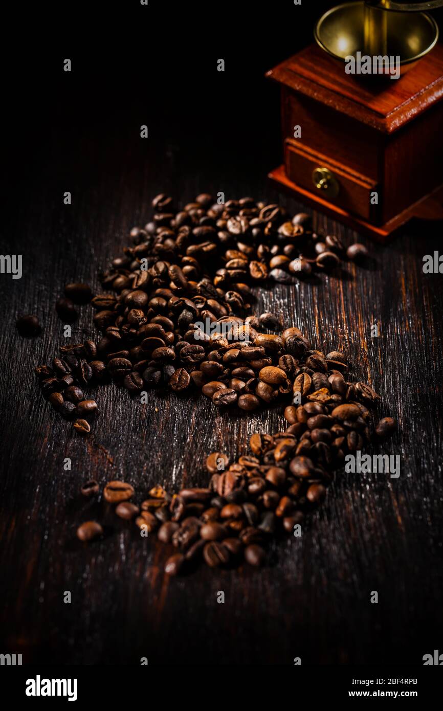 Kaffeebohnen auf dunklem Hintergrund mit Kaffeemühle Stockfoto