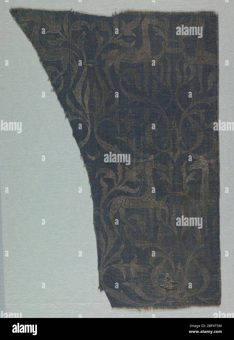 Fragment. Grobes dunkelblaues Leinen mit silberfarbenem Design. Paarweise konfrontierte Hirsche (oder Pferde) mit flankierenden Blattschilzen. Stockfoto