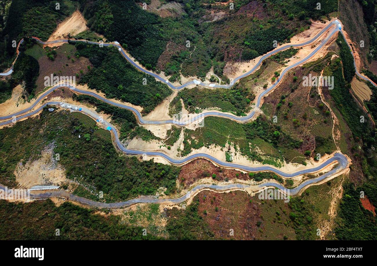 (200417) -- NANNING, 17. April 2020 (Xinhua) -- Luftaufnahme vom 18. März 2018 zeigt eine Landstraße im Dorf Nameng im Landkreis Napo, Südchina der autonomen Region Guangxi Zhuang. Obwohl die Provinz Guangdong an der Grenze zum reichen Land liegt und eine 1,500 Kilometer lange Küste hat, ist die autonome Region Guangxi Zhuang eine bergige Region, die seit langem von Armut geplagt ist. Die Verkehrsschwierigkeiten blieben ein Haupthindernis für die ländliche Entwicklung, vor allem in den von Bergen umschlossenen ländlichen Gebieten in Guangxi. Unzureichende Zufahrt zur Straße war üblich, und die meiste Zeit mussten die Leute laufen. Viele Straßen waren eithe Stockfoto