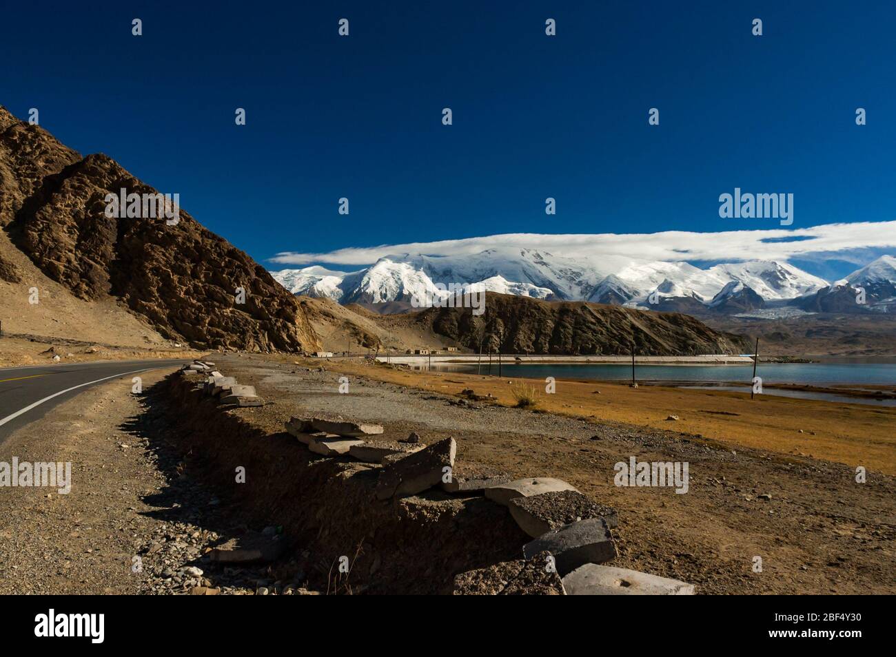 Wolke bedeckt Berge im Bereich von Pamir mit dem Karakorum Highway schlängelt um Kakakul See im Vordergrund. Xinjiang Stockfoto