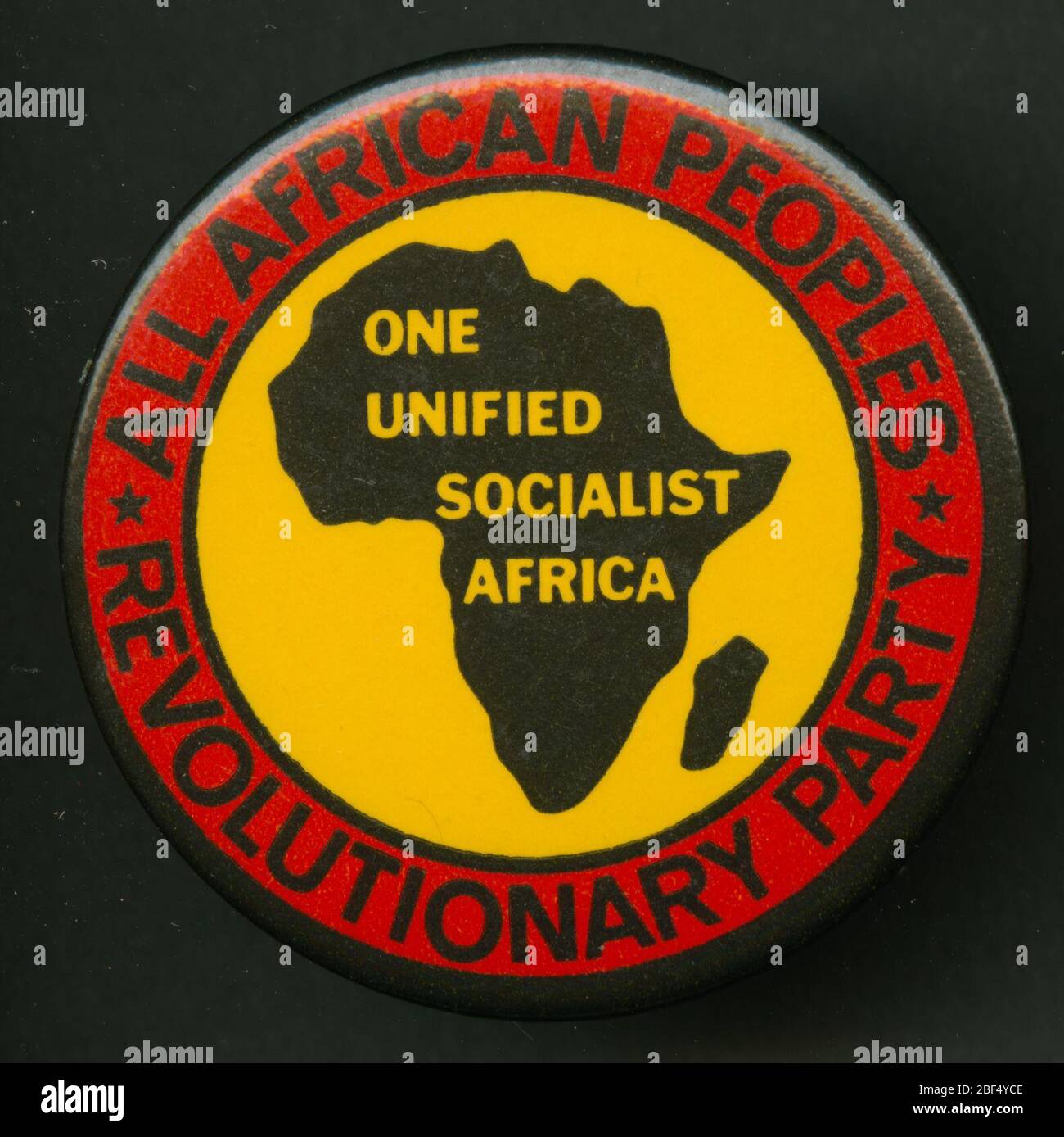 Pinback-Taste Förderung der AllAfrican Peoples Revolutionary Party. Runder Pin-Back-Knopf mit schwarzer Umrandung von Afrika auf gelbem Hintergrund. Gelbe Schrift erscheint im Afrika-Umriss und lautet: [ONE/UNIFIED/SOCIALIST/AFRICA]. Stockfoto