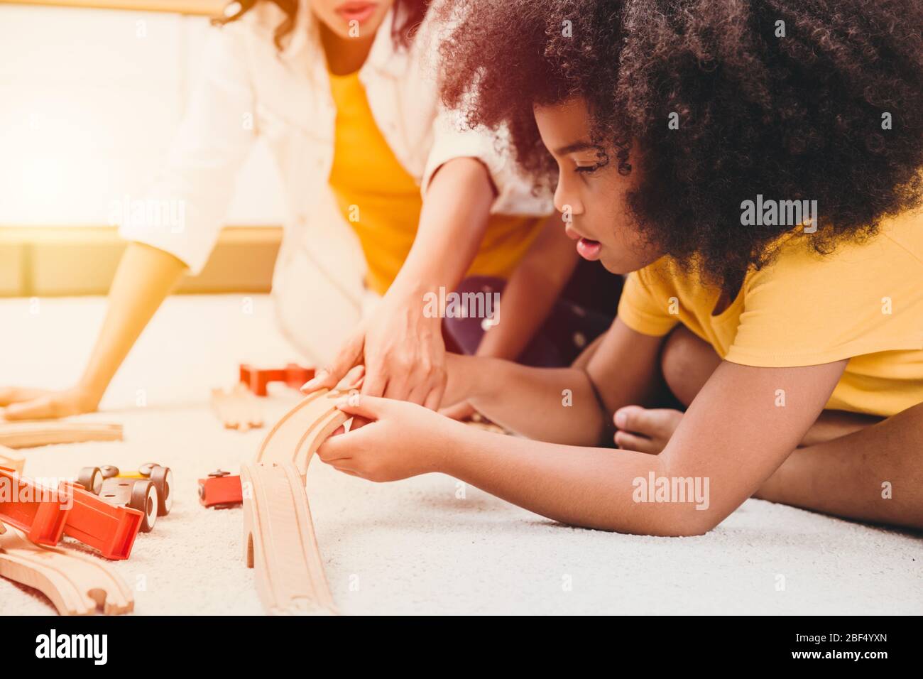Alleinerziehende Mutter lebt mit zwei Tochter, die Puzzle-Spielzeug in der Wohnung lernt und spielt. Nanny suchen oder Kinderbetreuung im Wohnzimmer schwarze Menschen. Stockfoto