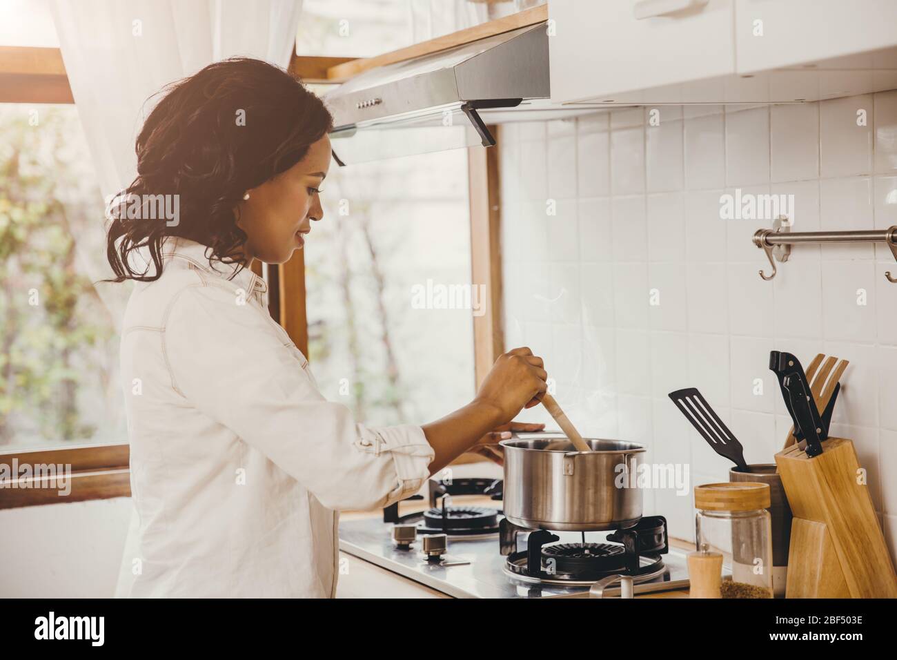 African American Black Frau Kochen kochende Suppe in der Küche zu Hause. Stockfoto