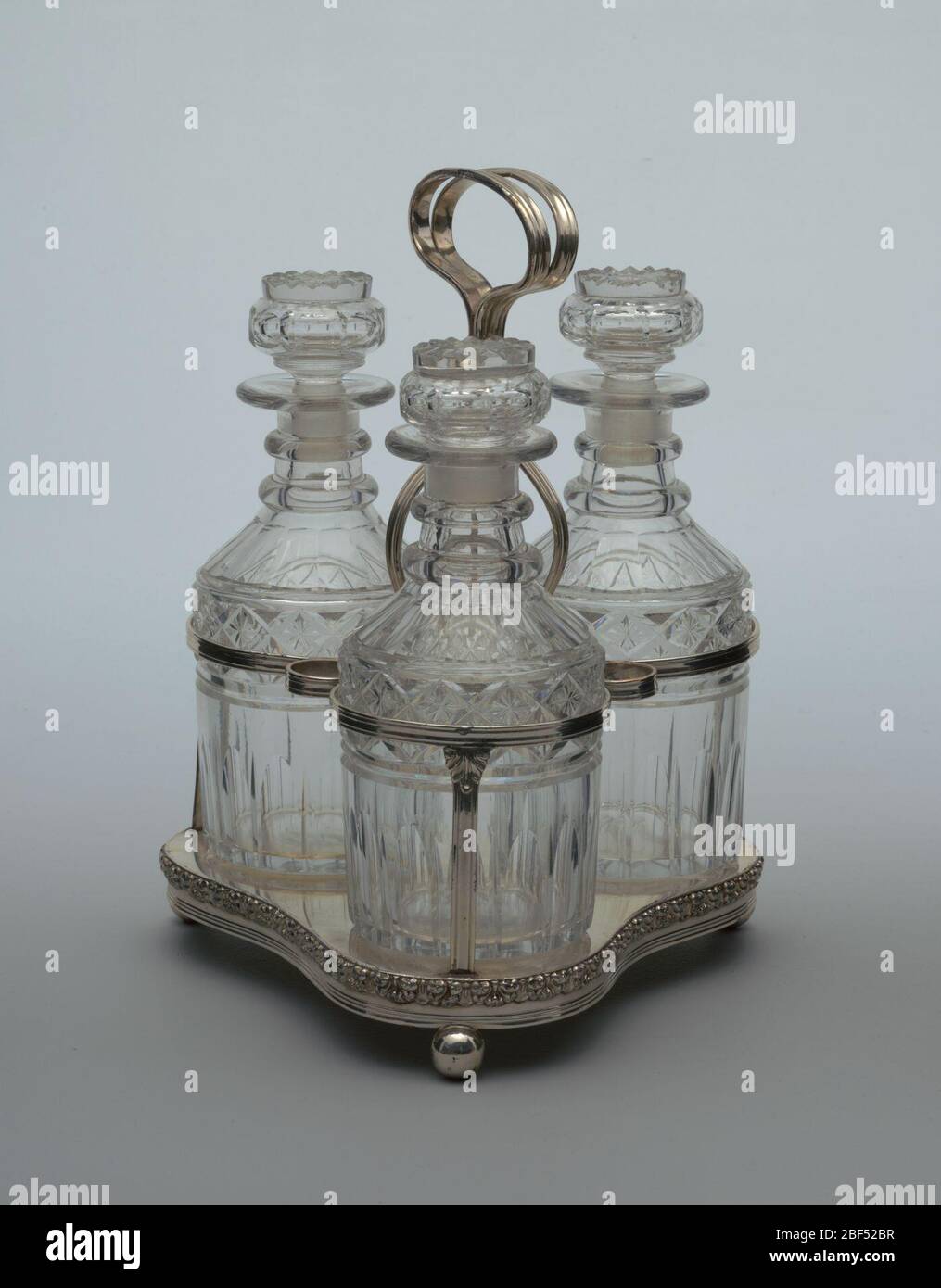 Ständer. Dreifach geformter Fuß mit applizierten geformten Rand, drei Kugelfüße; mit Reedrahmen für 3 Dekanter und Stopper, hoher zentraler Rundgriff. Stockfoto