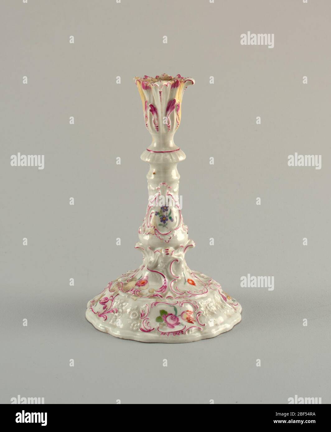 Kerzenständer mit Blumendekor. Kerzenständer mit breitem Sockel. Und geformte Blumen- und Scrollwork-Dekoration. In der Mitte eine Rocaille Kartusche, die bemalte Blumen umschließt. Stockfoto