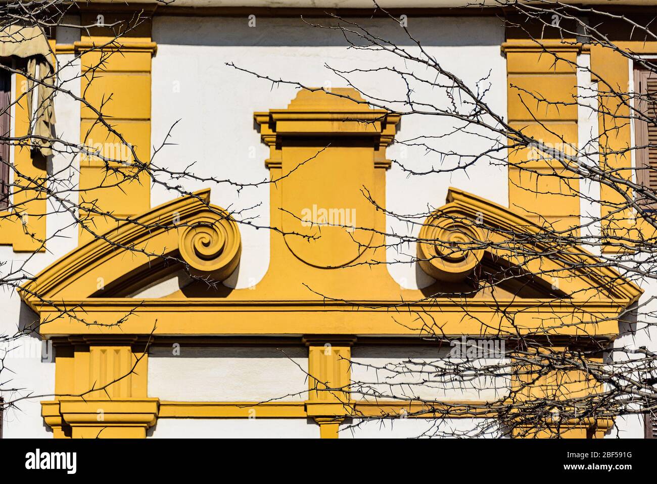 Gelber Giebel über einem Eingang in einem gekrümmten und gebrochenen Apex-Stil, der einer Person ähnelt, die seine Armmuskeln beuge. Stockfoto