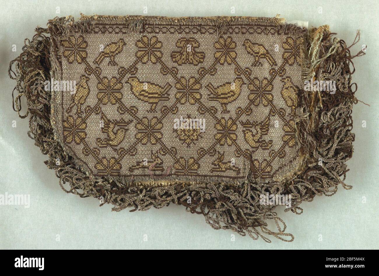 Einsätze für eine Tasche. Zwei identische Tafeln mit Vögeln, gekrönten Vögeln und floralen Motiven in Rautenraster in Gold und Schwarz auf silbernem Grund. Ein Stück ist auf drei Seiten mit goldmetallischen Fransen beschnitten. Stockfoto