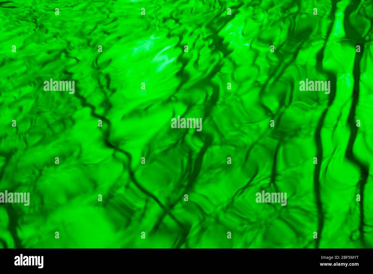 Abstrakte verwischte Bäume Spiegelung auf gewellten Wasseroberfläche in apfelgrünen Farbe Toning Stockfoto