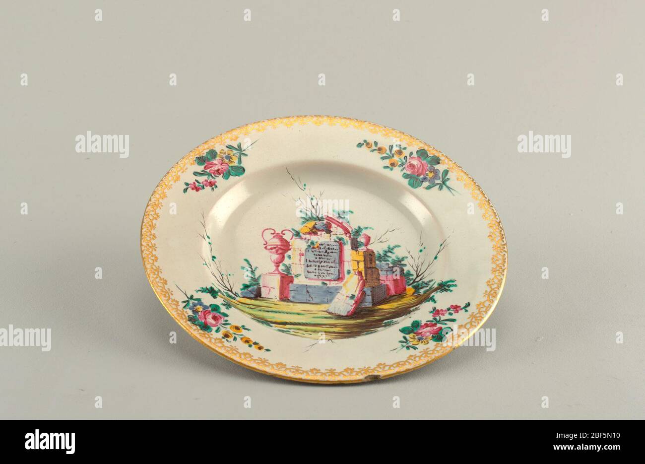Platte. Teller mit Blumensträußen auf marmeliertem und vergoldetem Rand. Im Zentrum, Ruinen in einer Landschaft. Stockfoto